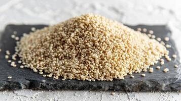 A mound of uncooked quinoa grains on a dark slate surface. photo