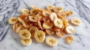 A pile of dried banana slices arranged on a marble surface. photo