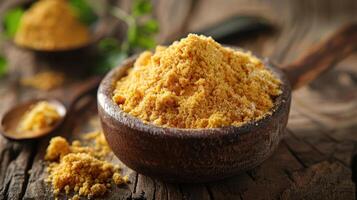 A wooden bowl filled with yellow powder, possibly a spice or seasoning, on a rustic surface. photo