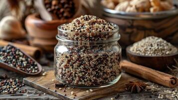 A jar of colorful quinoa surrounded by spices and natural elements on a rustic wooden surface. photo
