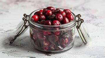 A glass jar filled with fresh and dried cranberries on a textured surface. photo