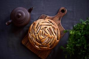 A fruit cake or a muffin or a pie with a clay pot and herbs. Flat lay. photo