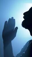 Silhouette of a man praying in dark space with holy backlight video