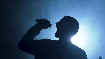 A Dynamic Silhouette of a Talented Singer Performing Boldly on Stage with a Bright Spotlight video