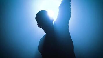 Striking silhouette of a person celebrating with raised arm with impressive source of blue light video