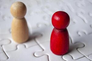 Close up of red and brown wooden dolls on jigsaw puzzle with customizable space for text photo