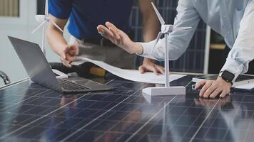 Two men working on a laptop and a wind turbine video