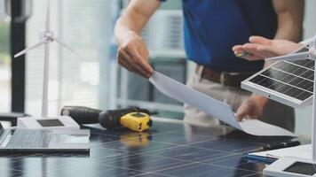 Two people working on a laptop with solar panels video