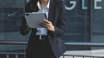 A woman in a business suit is holding a tablet video