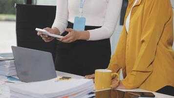 Two women standing at a desk with a laptop and papers video