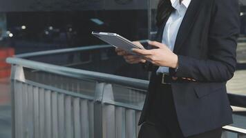 A woman in a business suit is holding a tablet video