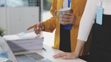 Two women are standing near a laptop computer video