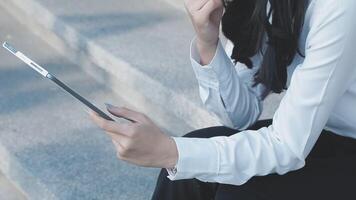 A woman in a business suit sitting on steps with her tablet video