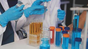 A group of people in lab coats and gloves are working on a test tube video