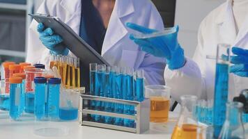 Two people in lab coats are working on a tablet video