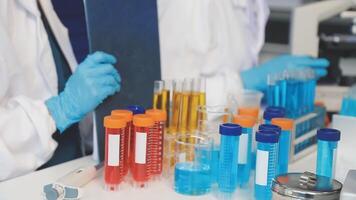 Two people in lab coats are working on a table with test tubes video
