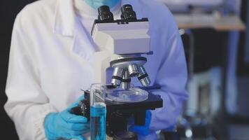 A person in a lab coat and gloves is looking at a microscope video