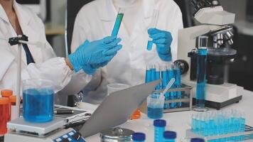 Two people in lab coats working on a computer video