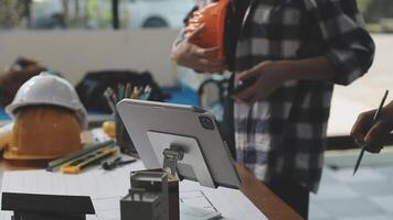 A man is working on a tablet while standing next to a man in a hard hat video