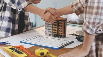 Two people shaking hands over a table with construction tools video