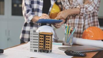 Two people are working on a project with a building model video