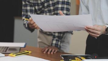 Two men are standing around a table with papers video