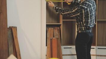 A man is measuring the height of a cabinet video