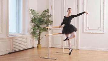 Young ballerina in tutu skirt stretching practicing ballet positions dancing near ballet barre in dance class. Young classical dancer woman in dance studio. Ballet class training Ballet school concept video