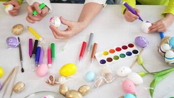 Happy Easter. Little girls grandmother hands painting eggs enjoying time together. Happy family preparing for Easter. Table with colorful painting eggs decorations. Spring Christian festival tradition video