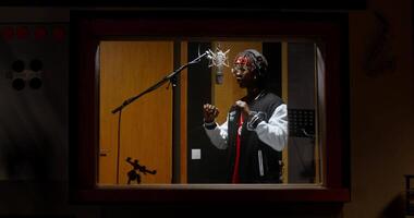 A man singing in a recording studio with a microphone video