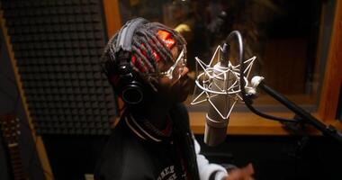 A man with dreadlocks is singing into a microphone video