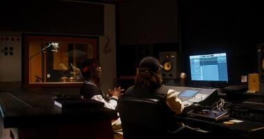Two people in a recording studio with a computer monitor video