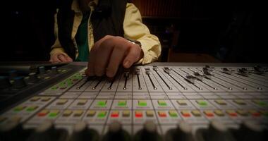 A person is working on a sound board in a recording studio video