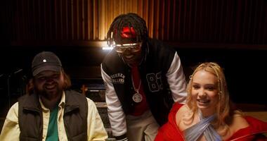 Three people posing for a photo in a recording studio video