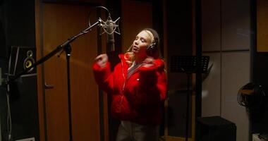 A woman in a red jacket singing into a microphone video