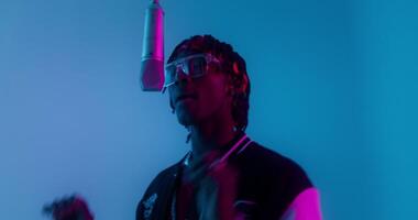 A man with dreads and glasses is singing into a microphone video