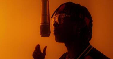 A person with dreadlocks and glasses is singing into a microphone video