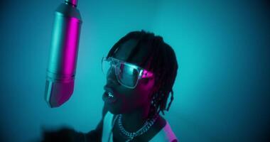 A man with dreadlocks and glasses is singing into a microphone video