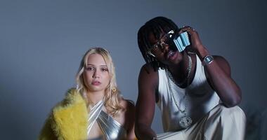 A man and woman posing for a photo in front of a camera video