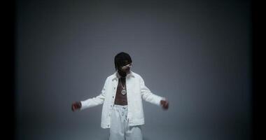 A man in white pants and jacket standing in front of a white background video