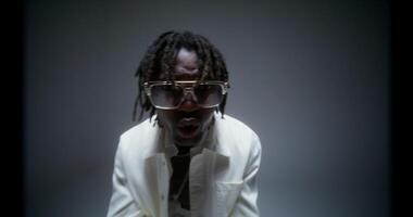 A man with dreadlocks and glasses is making a face video