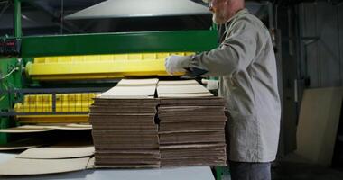 A man is working on a machine that is making cardboard boxes video