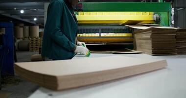 A worker is working on a machine that is making cardboard video