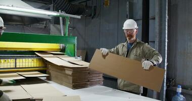 Two men in hard hats working on cardboard boxes video