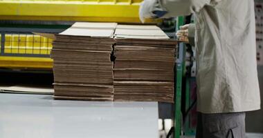 A worker is loading cardboard boxes onto a conveyor belt video