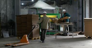 Two workers in a factory with cardboard boxes video