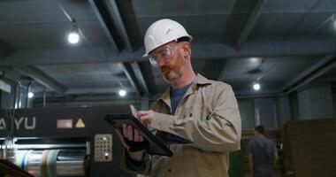 A man in a hard hat and helmet using a tablet video