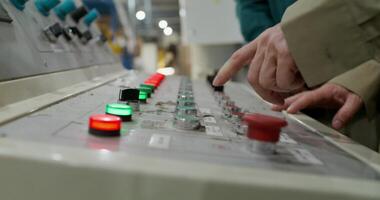 A person is pointing at a control panel in a factory video
