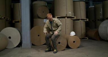 A man sitting on top of a pile of rolls of paper video