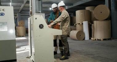 Two men in hard hats working on a machine video